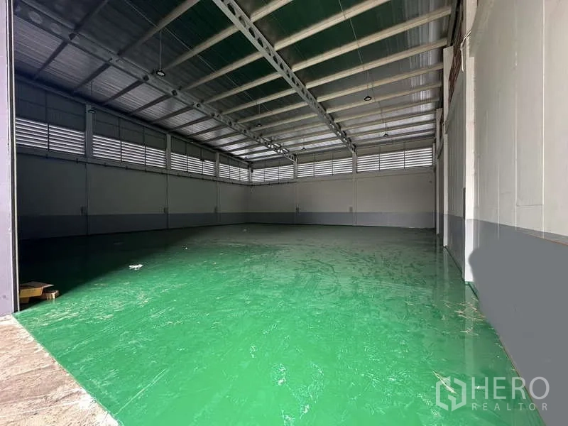Factory for rent in Lam Luk Ka, Pathum Thani - Spacious warehouse interior with high steel truss roof and green epoxy floor.