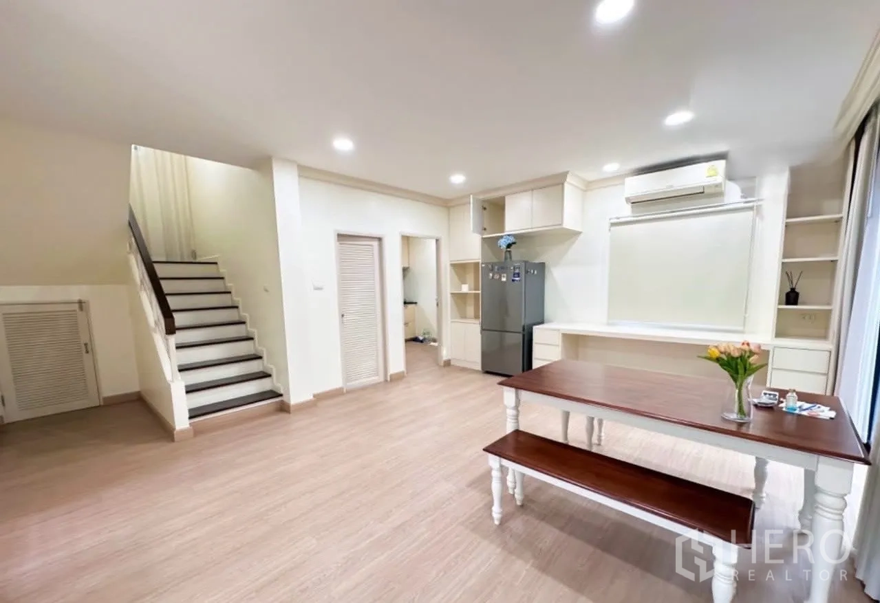 Detached House for sale in Lam Luk Ka, Pathum Thani - Ground floor view with staircase, dining table, built-in cabinetry and access to a utility room.
