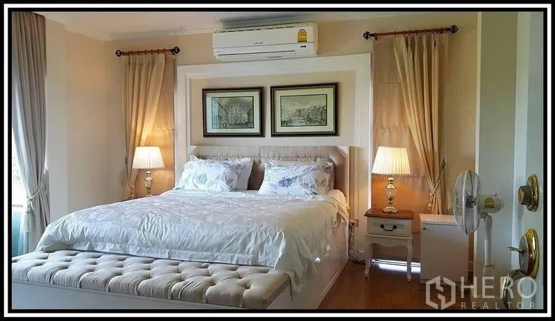 Detached House for sale in Lam Luk Ka, Pathum Thani - Serene master bedroom with king bed, tufted bench, bedside lamps and air-conditioning.