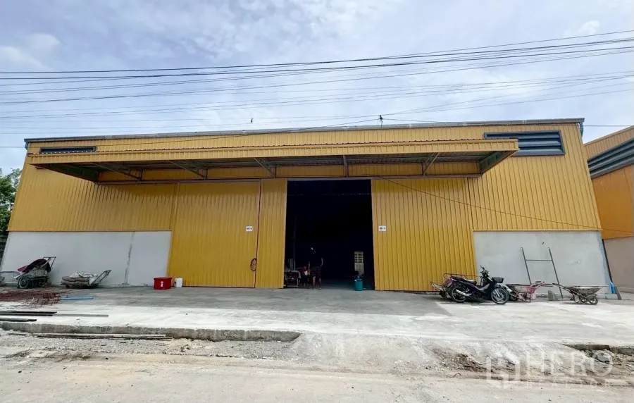 Warehouse for rent in Khlong Luang, Pathum Thani - Front view of a yellow metal-clad warehouse with wide sliding doors and a loading apron.