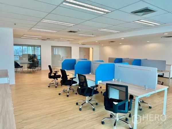 Office Space for rent - Bright open-plan office with blue and gray partitioned workstations, chairs and a glass meeting room.
