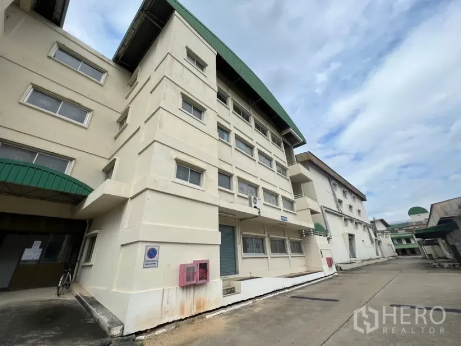 Warehouse for rent in Bang Kapi, Bangkok - Main facade of industrial building with green canopies and a service lane for truck access.
