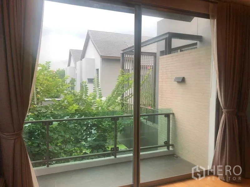 Detached House for rent or sale in Bang Kapi, Bangkok - Balcony with glass railing overlooking trees and neighboring houses.
