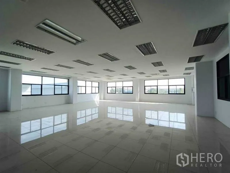 Warehouse for rent or sale in Pathum Thani - Open-plan office floor with large windows and grid lighting.