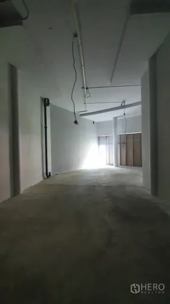 Retail Space for rent in Khlong Toei, Bangkok - Empty retail interior with bare‑shell finish, visible ceiling services and daylight near the entrance.