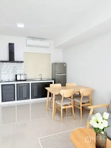 Townhouse for rent in Bang Phli, Samut Prakan - Fitted kitchen with black cabinets, subway-tile backsplash and dining set.