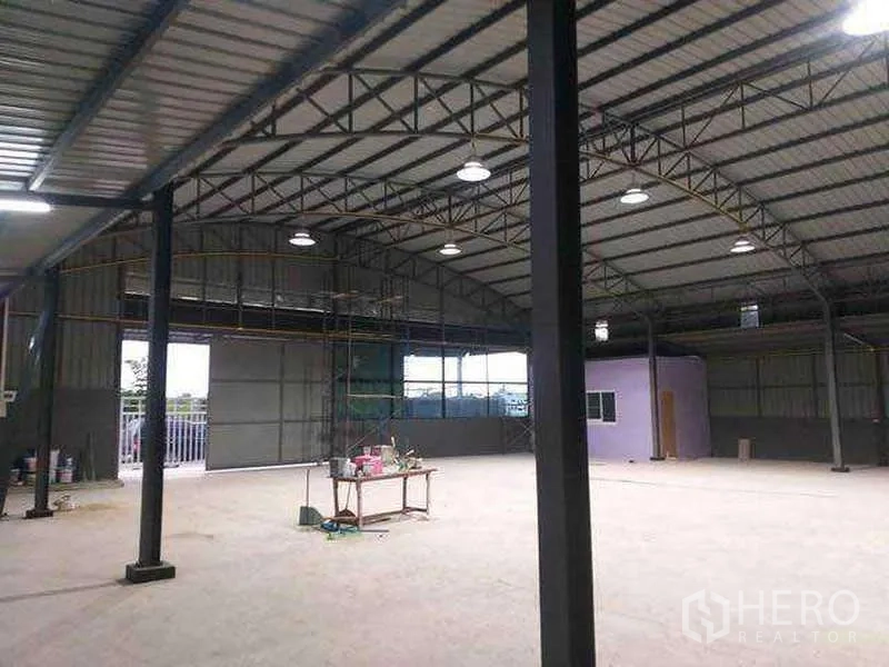 Warehouse for rent in Khlong Sam Wa, Bangkok - Warehouse interior with steel columns, small built‑in office room and loading access doors.