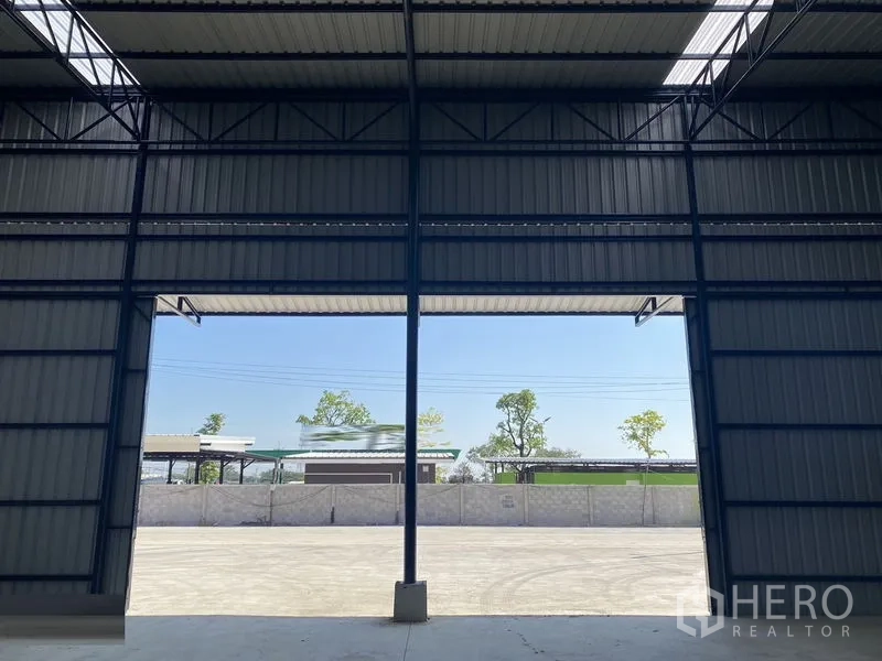 Warehouse for rent in Ban Pho, Chachoengsao - Interior of a new steel-frame warehouse with high-clearance opening to a large concrete yard in Ban Pho, Chachoengsao.