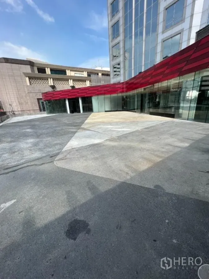 Retail Space for rent in Pathum Wan, Bangkok - Modern retail frontage with red canopy and wide open plaza beside a glass-clad building.