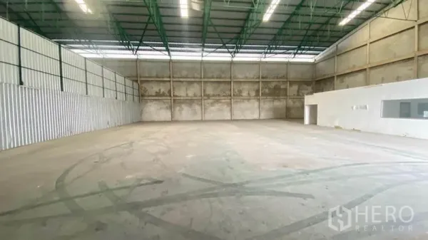 Warehouse for rent in Samut Prakan - Spacious warehouse interior with high steel truss roof and concrete walls.