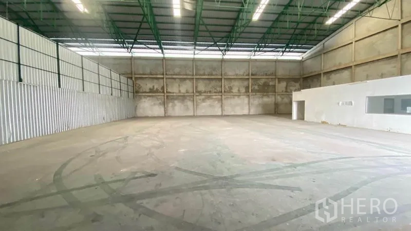 Warehouse for rent in Samut Prakan - Spacious warehouse interior with high steel truss roof and concrete walls.