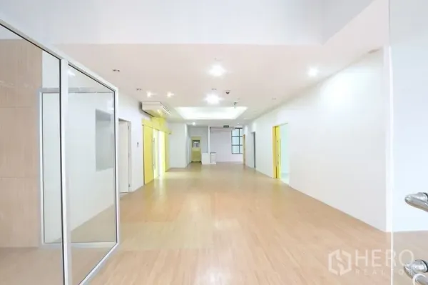 Office Space for rent in Bang Na, Bangkok - Bright open‑plan corridor with wood flooring, recessed lights and glass partitions ready for meeting rooms.