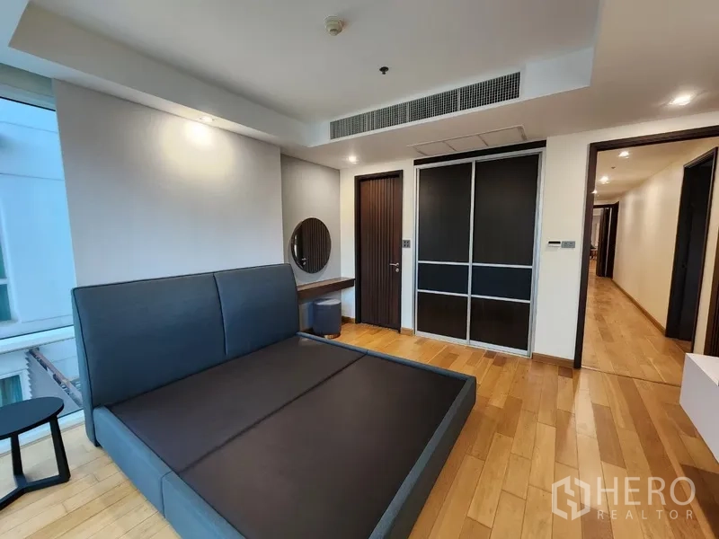 Condominium for rent in Khlong Toei, Bangkok - Bedroom with sliding wardrobe doors and wood flooring.