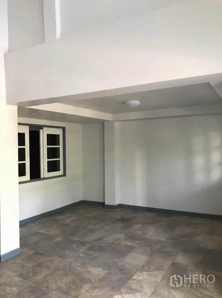 联排别墅 出租在Suan Luang, Bangkok - 一层开放式起居区，地砖、白墙与嵌入式天花。
