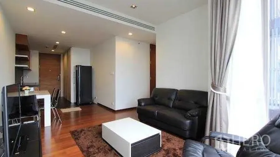 Condominium for rent - Living area toward entry with sofa, TV and dining table near floor‑to‑ceiling windows.