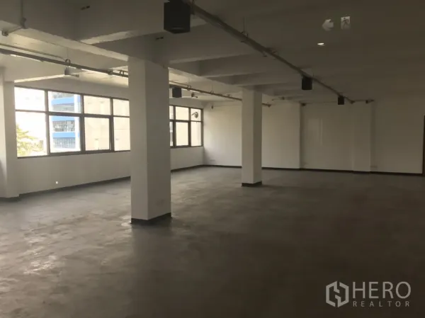 Office Space for rent in Khlong Toei, Bangkok - Spacious vacant office level with support columns, track lighting and wall‑length windows.