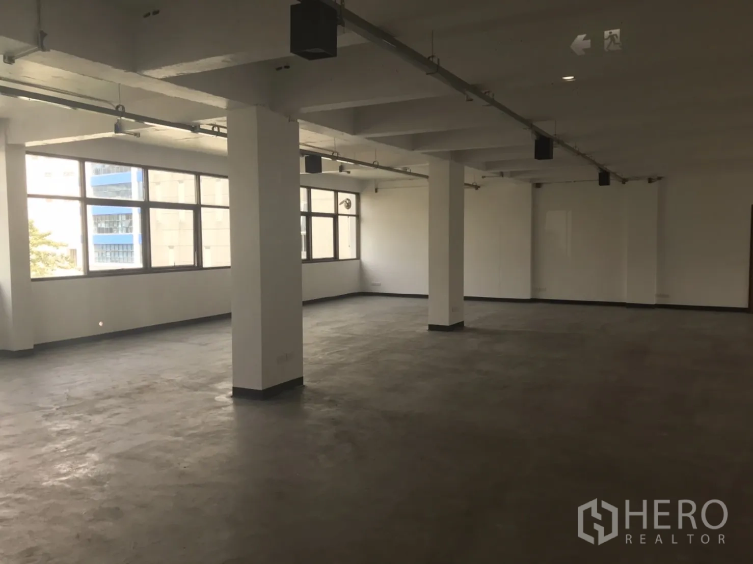 Office Space for rent in Khlong Toei, Bangkok - Spacious vacant office level with support columns, track lighting and wall‑length windows.
