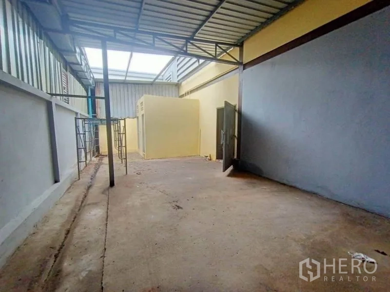 Factory for rent or sale in Mueang Samut Sakhon, Samut Sakhon - Rear service yard under a metal roof with utility room and access doors.