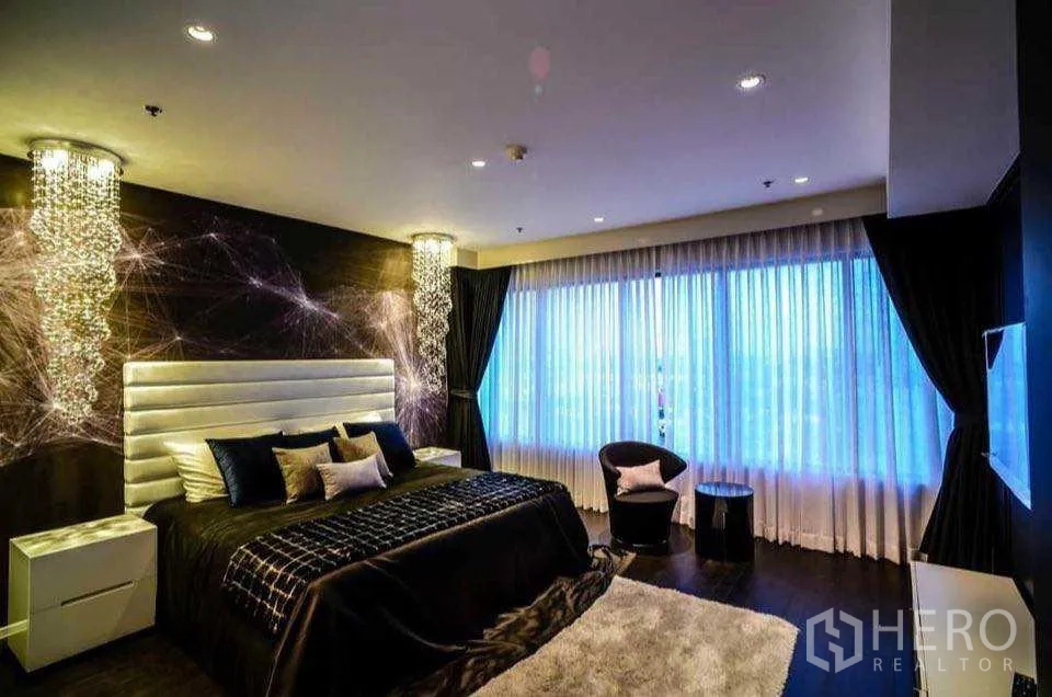 Condominium for rent or sale in Khlong Toei, Bangkok - Primary bedroom with large windows, feature wall and crystal ceiling lights.