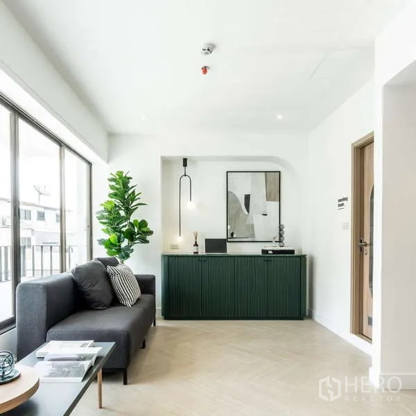 Office Space for rent in Watthana, Bangkok - Reception lounge featuring a grey sofa, large windows, and a dark green counter.
