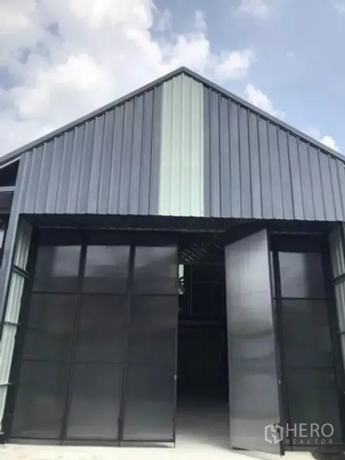 Warehouse for rent in Chatuchak, Bangkok - Modern metal-clad warehouse facade with high gable roof and wide sliding doors open.