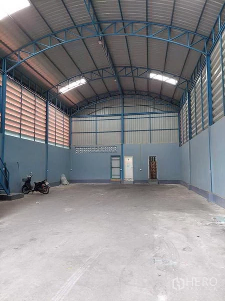 Warehouse for rent or sale in Bang Bua Thong, Nonthaburi - Spacious clear-span warehouse featuring tall steel trusses, skylights, and ventilated walls.
