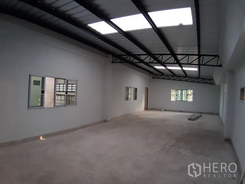 Warehouse for rent in Chatuchak, Bangkok - Large upper‑floor office or storage room with skylights and exposed metal roof beams.
