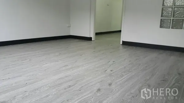 Shophouse for rent in Watthana, Bangkok - Close-up of light gray wood-look vinyl flooring and black skirting boards.