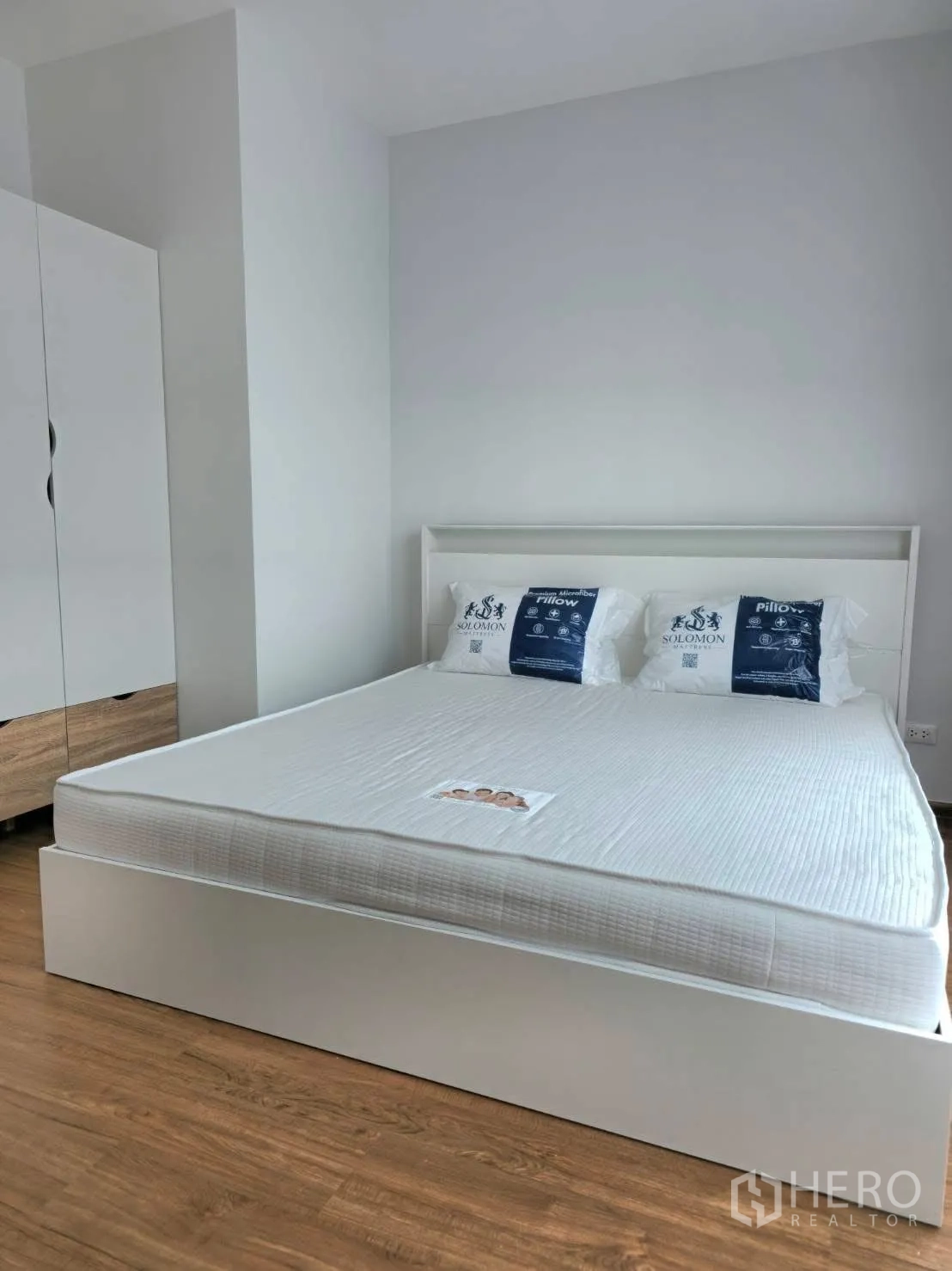 Townhouse for rent in Bang Phli, Samut Prakan - Master bedroom with a white bed, wardrobe and wood-look flooring.