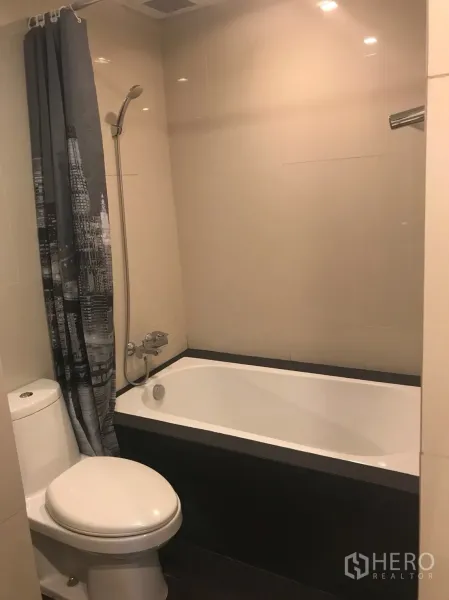 Condominium for rent in Khlong Toei, Bangkok - Bathroom fitted with bathtub, handheld shower and tiled walls.