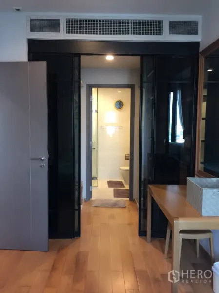 Condominium for rent in Khlong Toei, Bangkok - Bedroom corridor with glass partitions leading to a contemporary bathroom.