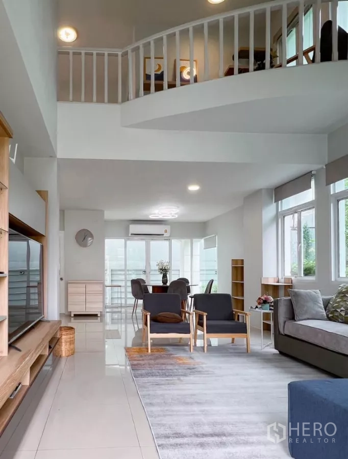 Detached House for rent or sale in Prawet, Bangkok - Long view from living to dining area with mezzanine and glossy tiled floors.