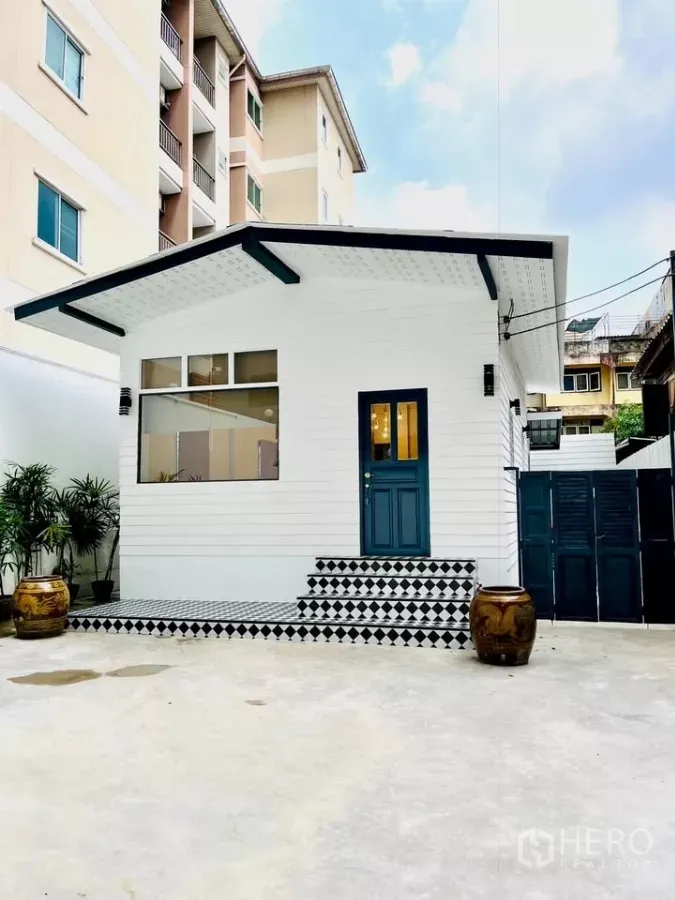 Detached House for rent - Front view of a newly refreshed white detached house with blue door and checkered steps in Sathorn, Bangkok.