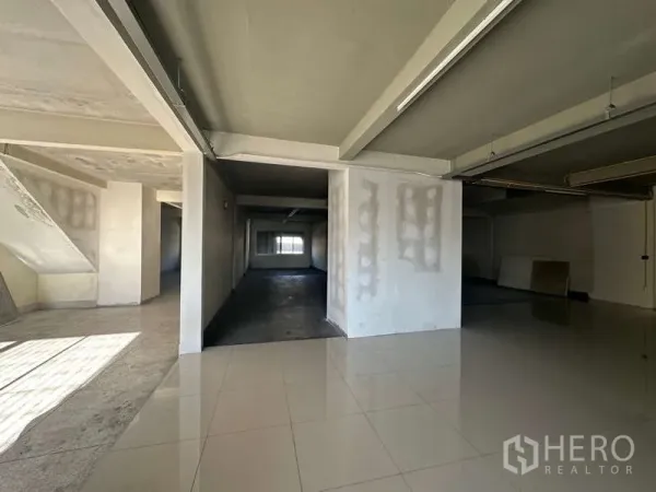 Office Space for rent in Phra Khanong, Bangkok - Open-plan office floor with mixed tiled and concrete surfaces, exposed beams and strip lighting.