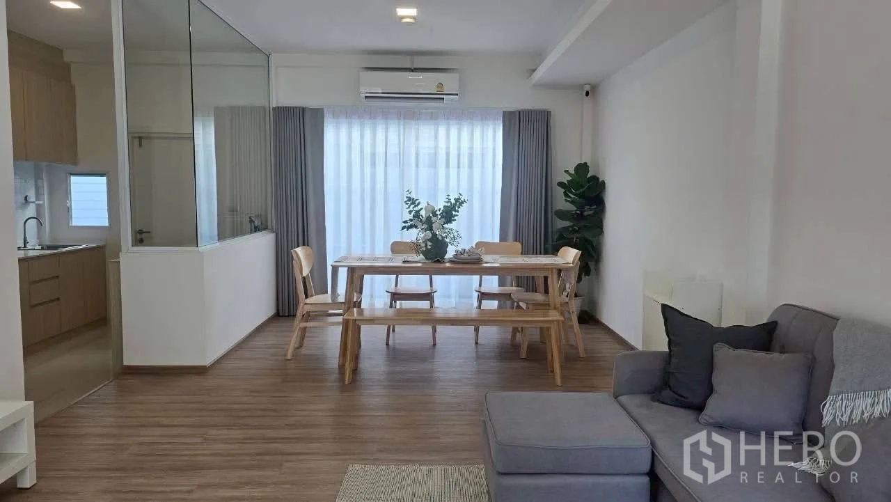 联排别墅 for rent in Prawet, Bangkok - 客餐厅一体，厨房以玻璃隔断，搭配落地窗帘。
