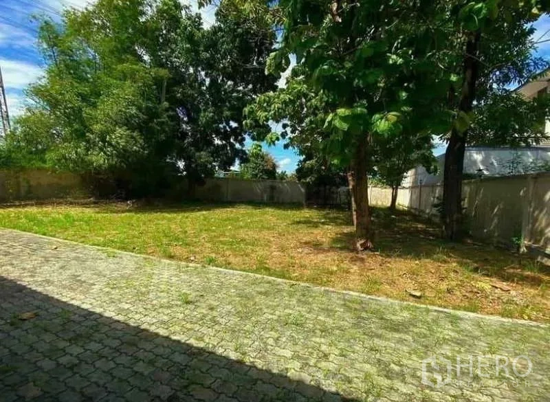 Detached House for sale in Prawet, Bangkok - Large garden with lawn, mature trees, and a paved driveway inside the compound.