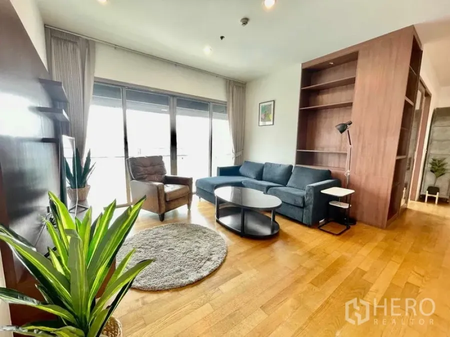 Condominium for rent in Watthana, Bangkok - Sunlit living room with sofa set, coffee table and balcony access.