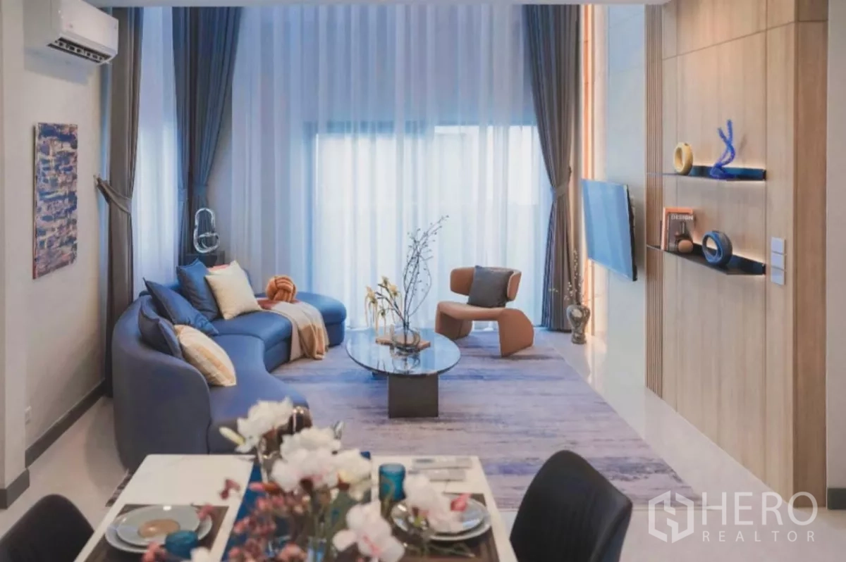 Detached House for rent in Bang Phli, Samut Prakan - Bright open-plan living and dining area with large curtains, blue sofa and glass coffee table.