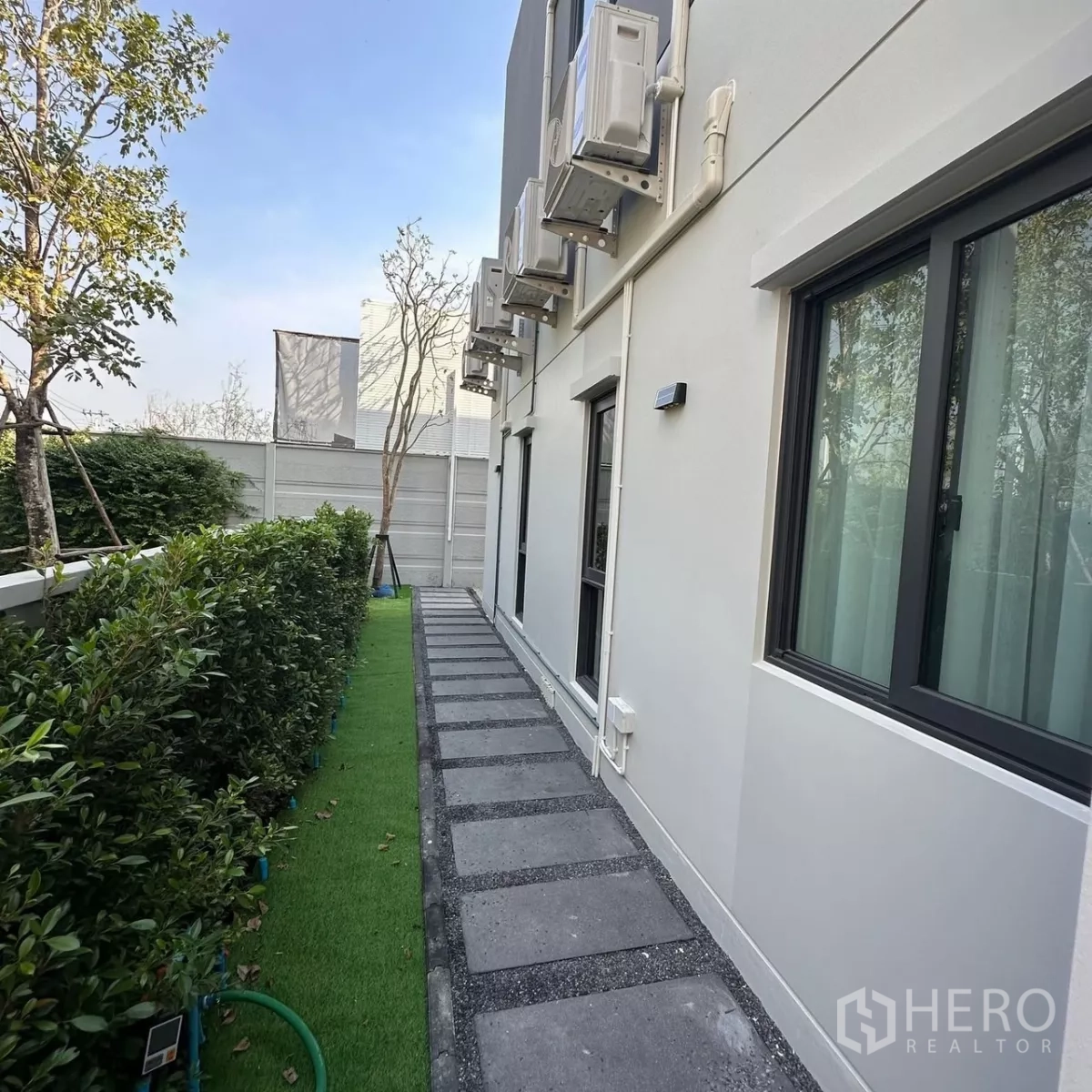 Detached House for rent in Bang Phli, Samut Prakan - Side garden walkway with stepping stones, shrubs and exterior AC units.