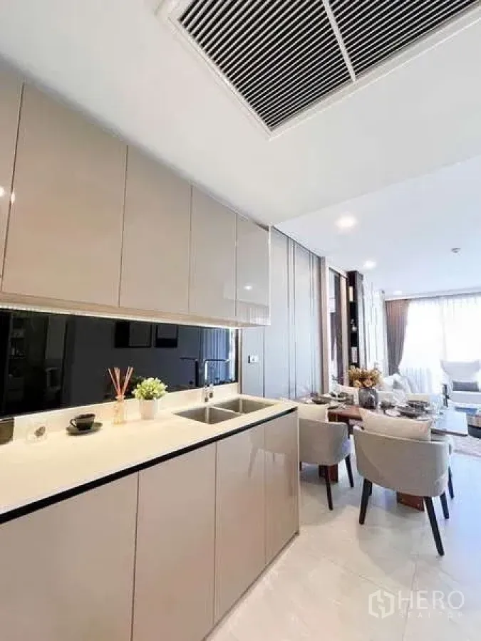 Condominium for rent in Watthana, Bangkok - Minimalist kitchen with glossy cabinets, sink and counter facing the dining area.
