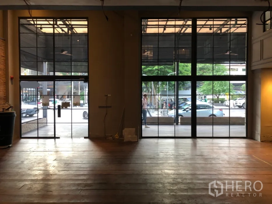 Retail Space for rent in Khlong Toei, Bangkok - Spacious retail interior with floor-to-ceiling steel-framed windows and wood flooring facing the street.