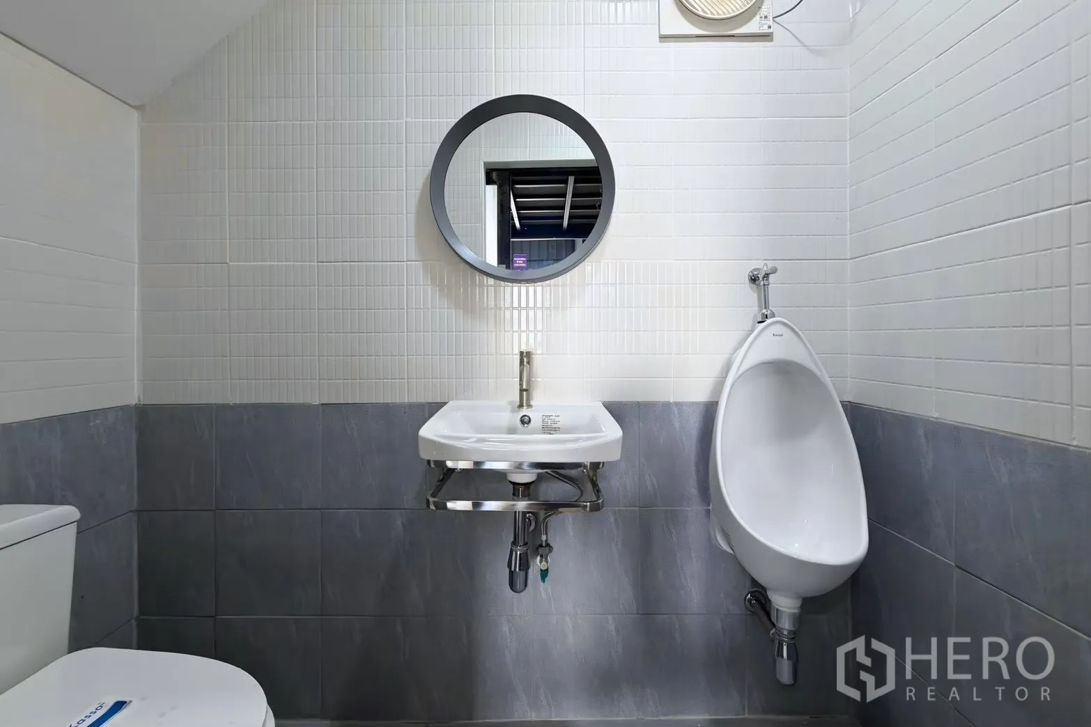 Warehouse for rent in Suan Luang, Bangkok - Restroom with toilet, urinal, wall-mounted sink, mirror, and tiled walls.