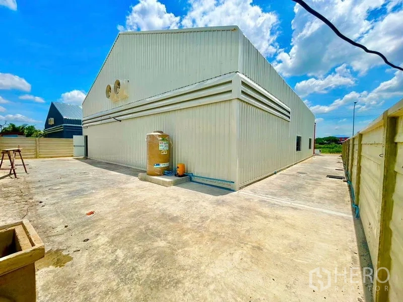 货栈 出租在Lam Luk Ka, Pathum Thani - 仓库侧面，围墙内的混凝土空地与水塔区域。