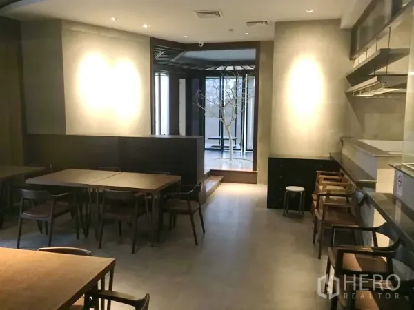 Retail Space for rent in Khlong Toei, Bangkok - Open dining area with wooden tables, chairs and accent lighting in a minimalist setting.
