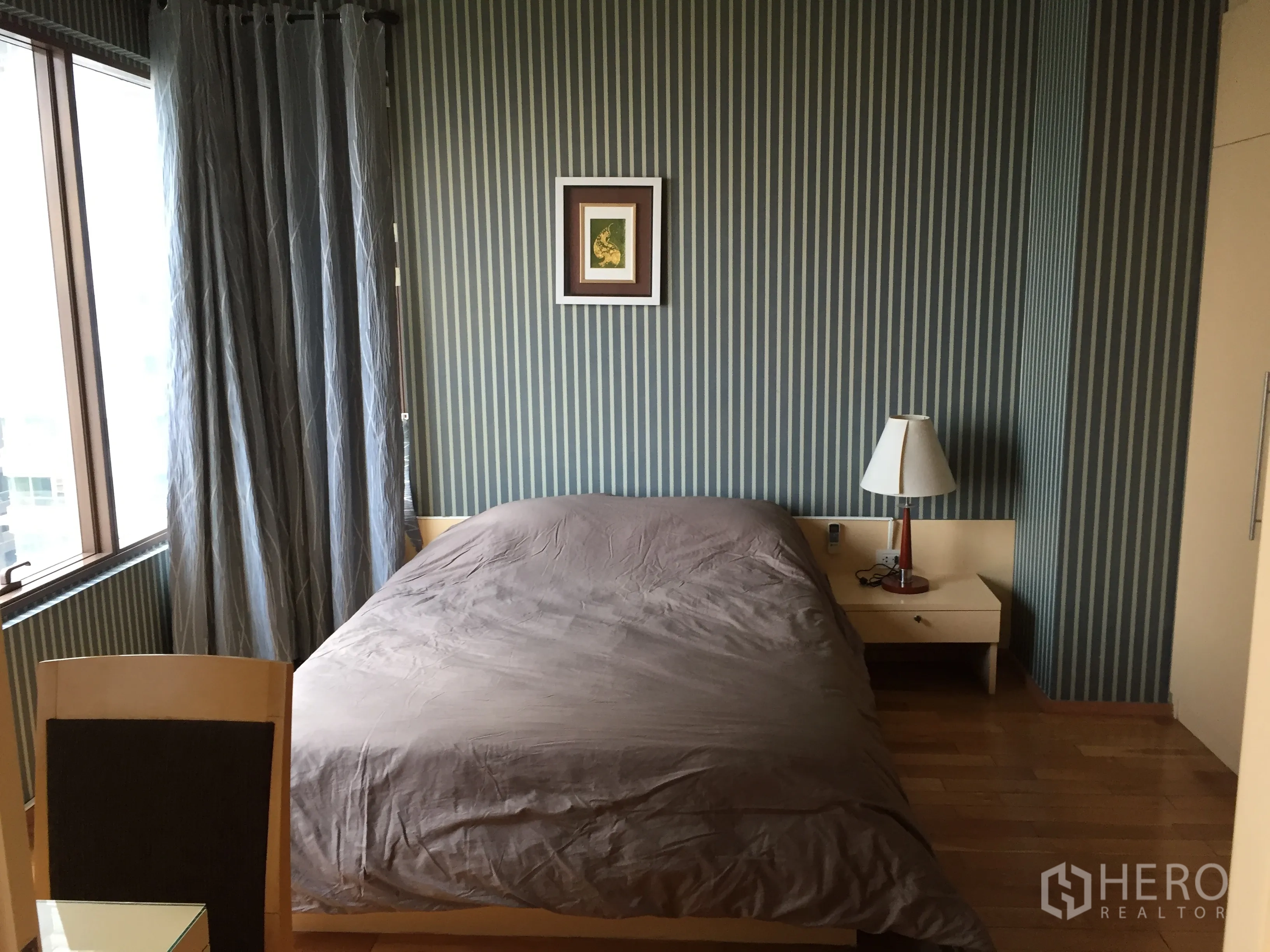 Condominium for rent or sale in Khlong Toei, Bangkok - Cozy bedroom featuring a double bed, bedside table and framed art against a striped accent wall.