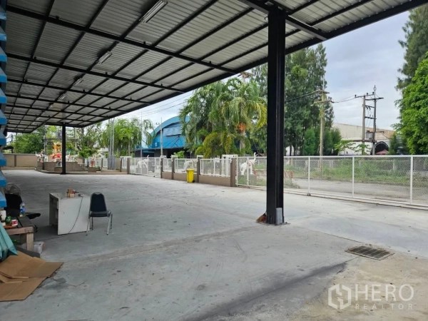 Factory for rent in Si Racha, Chon Buri - Spacious covered driveway along the factory with perimeter fencing and palm landscaping.