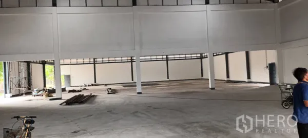 Warehouse for rent in Phra Pradaeng, Samut Prakan - Interior view showing open concrete floor, structural columns, and materials staged for work.