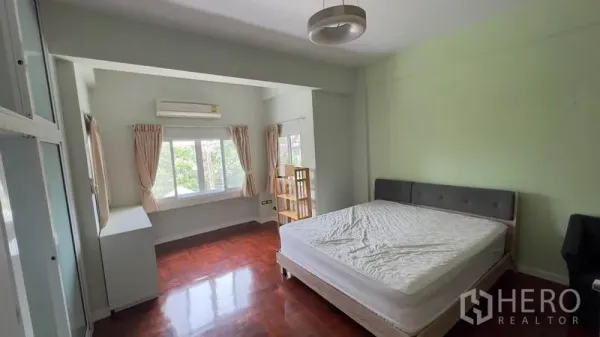 Townhouse for rent or sale in Khlong Toei, Bangkok - Spacious bedroom with big windows, air conditioning and polished wood floors.