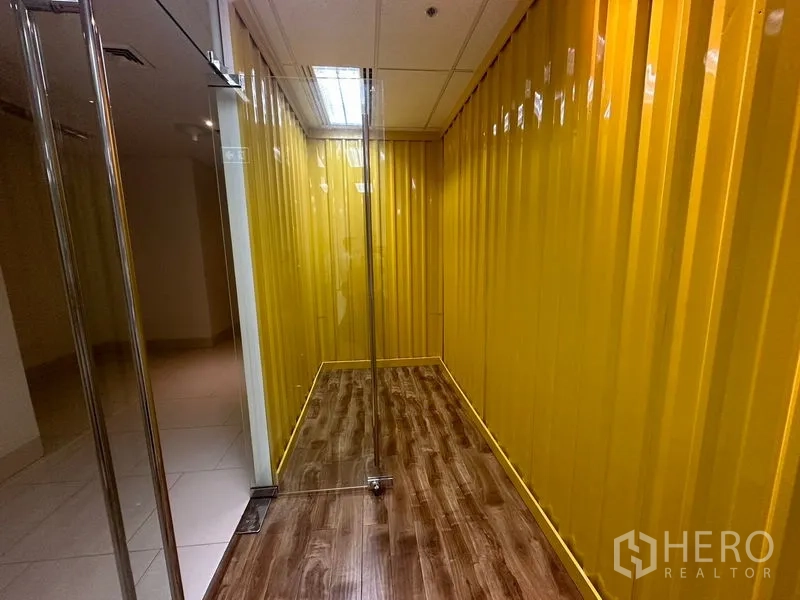 Office Space for rent in Chatuchak, Bangkok - Narrow corridor finished with glossy yellow paneled walls and a frameless glass door.