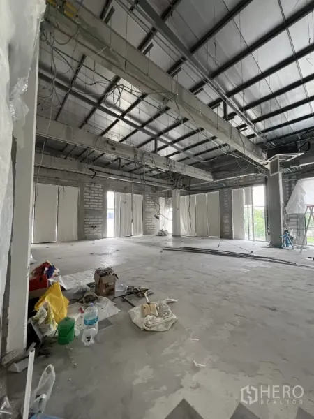 Retail Space for rent in Khlong Toei, Bangkok - Unfinished retail space showing exposed beams, wiring and multiple windows with construction materials on the floor.